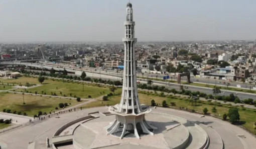 Towering Minar-e-Pakistan with a green park backdrop.