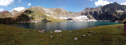 Pristine turquoise waters of Ratti Gali Lake surrounded by snow-capped mountains in Azad Kashmir.